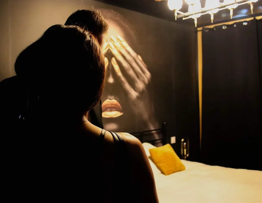 Femme assise sur un lit dans une chambre LW House avec fresque murale artistique