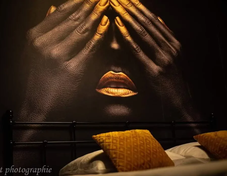 Chambre LW House avec fresque murale artistique au-dessus du lit et coussins dorés